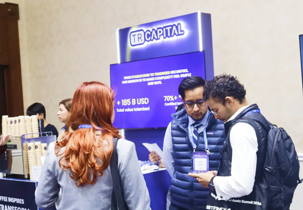 Visitantes conversando con el equipo de TR Capital en el stand de la empresa